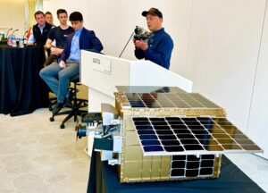 Show-and-tell panel with Paul Mikesell at podium and Otter Pup spacecraft in foreground