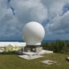 Bulb-shaped radio antenna dome with ocean in the far background