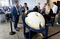 Space Northwest Symposium attendees in the lobby of a conference hall with Varda space capsule on display