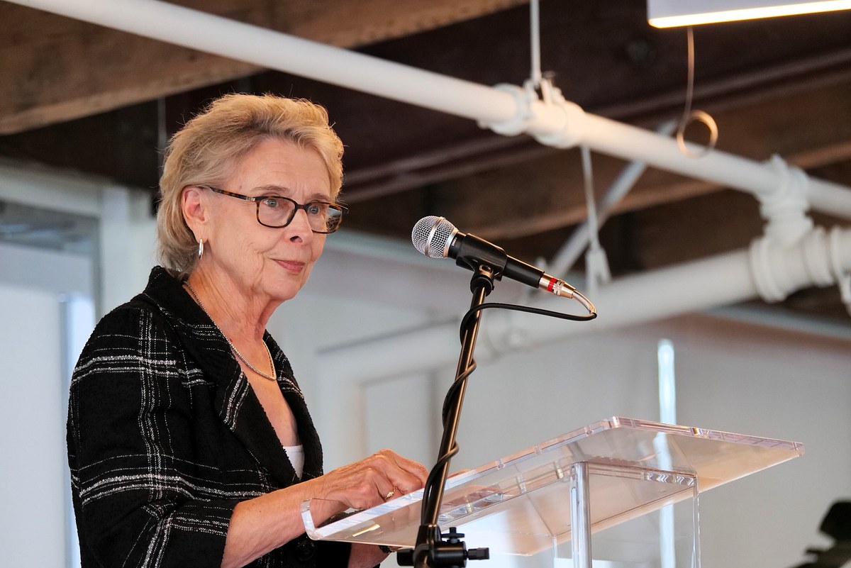 Chris Gregoire speaks at a clear podium with a microphone.