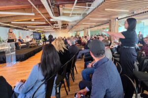 A protester stands in the audience and points toward the stage during a panel discussion at AI House in Seattle.