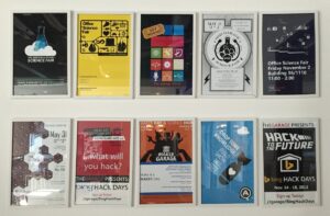 Ten framed posters for Microsoft Garage science fairs and hack days hanging in two rows on a white wall.