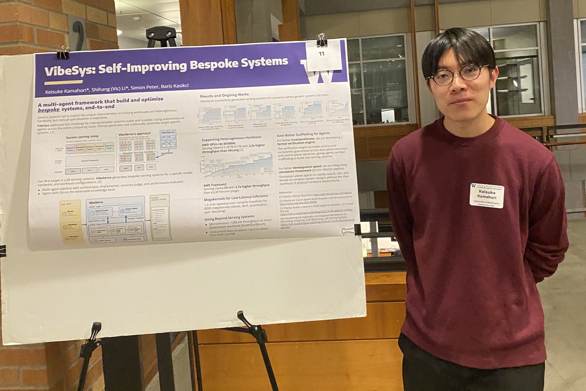 A student in a maroon sweater stands beside a research poster